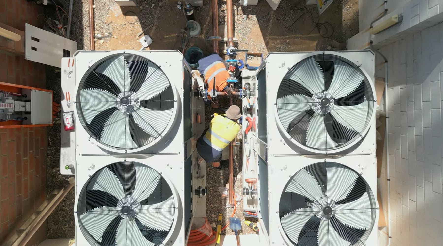 A refrigeration mechanic repairs a large air conditioning unit in Perth, providing HVAC insurance and repair services efficiently